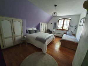 Dormitorio púrpura con 2 camas y ventana en Gite des écureuils, en Obernai