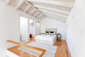1 dormitorio blanco con 1 cama y suelo de madera en D. João IV Apartments by LovelyStay, en Oporto
