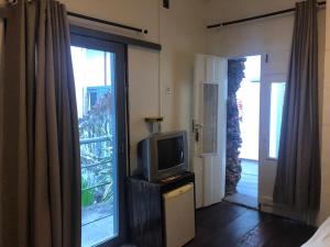 a room with a tv and a door with a window at Palma Hostel in São Luís