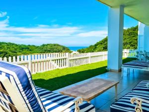 a porch with chairs and a table and the ocean at Villa 44, The Estuary Country Estate, Port Edward in Port Edward