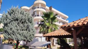 a large white building with trees in front of it at Talia apartments & pool in Dobra Voda