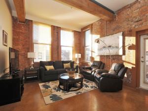 a living room with leather furniture and a brick wall at Just Listed! Gorgeous Luxury 2 Bedroom, 2 Bath Condo In Old Town Victoria in Victoria