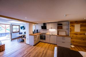 cocina con armarios blancos y suelo de madera en Gästehaus Holzer Kreuz- Vergissmeinnicht en Fröhnd