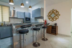 a kitchen with a bar with three stools at Cozy Apartments at East Airport in Burma Camp