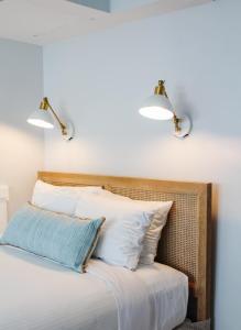 Duas luzes por cima de uma cama com almofadas brancas em The Inn Of Cape May em Cape May
