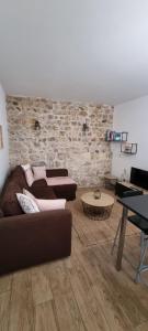 a living room with two couches and a brick wall at Appartement chaleureux en Ardèche in Châteaubourg