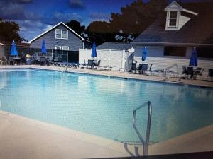 una gran piscina con sillas y sombrillas azules en Dorothy and Johns Ocean City Md Vacation Home Sleeps 8 - 3 bedrooms 2 full bath, en Ocean City