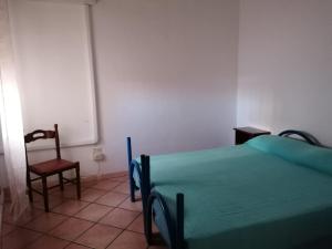 ein Schlafzimmer mit einem Bett, einem Stuhl und einer Tafel in der Unterkunft Appartamento Bent el Rhia in Pantelleria