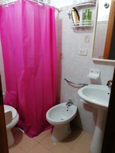 einen rosa Duschvorhang im Bad mit WC und Waschbecken in der Unterkunft Appartamento Bent el Rhia in Pantelleria