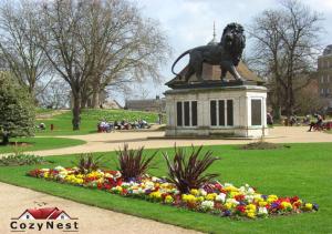 een standbeeld van een leeuw in een park met bloemen bij Charming 2 Bed 2 Bath Flat & Parking by CozyNest in Reading