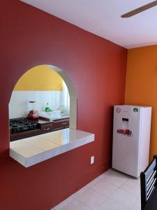 cocina con nevera blanca y paredes rojas en Sensity Home Casa confortable en Fracc Privado Céntrica, en Tehuacán