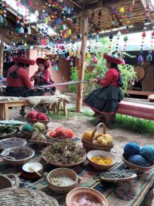 two women in hats sitting at a table with food at KanchayKillaWasi in Chincheros