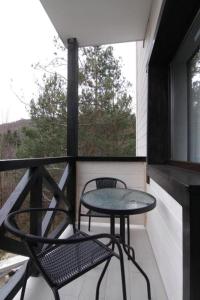 una mesa y una silla en un balcón con ventana en Villa Medova en Kosiv
