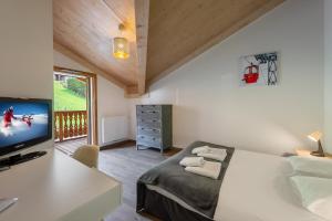 een slaapkamer met een bed en een bureau met een televisie bij Perle de savoie - Apt C706 - BO Immobilier in Châtel