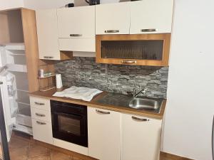 una cocina con armarios blancos y fregadero en Residence Sulcis 5, en Masainas