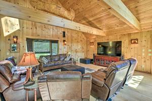 a living room with leather furniture and a flat screen tv at Serene Lakefront Cabin with Fire Pit and Kayaks! 