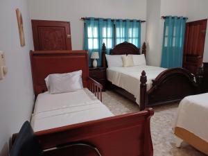 a bedroom with two beds with blue curtains at CerroAly in Santiago de los Caballeros