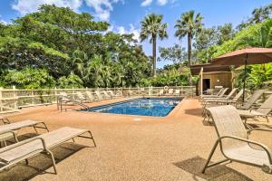 a swimming pool with chairs and an umbrella at Tropical Paniolo Hale Townhome, Walk to Beach in Maunaloa