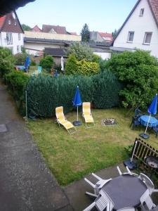 einen Hinterhof mit Stühlen, einem Tisch und blauen Sonnenschirmen in der Unterkunft Apartment 4 Langelsheim Harz in Langelsheim