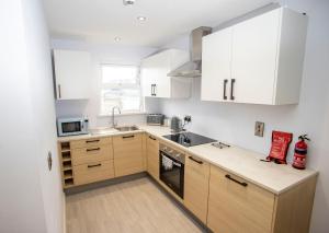 a small kitchen with white cabinets and a sink at Entire penthouse apartment with sea views Portrush in Portrush
