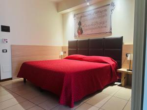 a bedroom with a bed with a red blanket on it at Albergo Visconti in Cremona