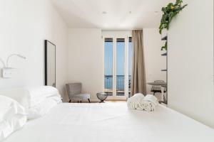 a white bedroom with a large bed and a balcony at La Vacanza Ortigia in Siracusa