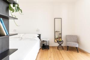 a bedroom with a bed and a mirror and a chair at La Vacanza Ortigia in Siracusa