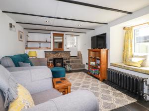 een woonkamer met een bank en een open haard bij Sanctuary Cottage in St Ives