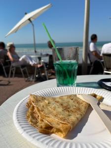 迪耶普的住宿－Le Gîte du Petit Buccin à 2 mn de la mer.，纸板上的一块比萨饼,配上一杯饮料