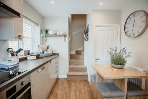 cocina con mesa y reloj en la pared en Lavender Lodge Bourton, en Bourton on the Water