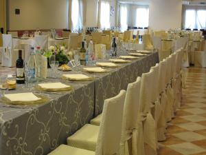 uma mesa longa com cadeiras brancas e garrafas de vinho em Park Hotel Italia em Tezze sul Brenta