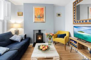 a living room with a blue couch and a fireplace at Hope Cottage, Brixham in Brixham
