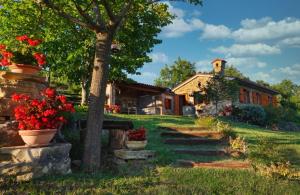 a house with a tree and flowers in a yard at House in Istria in pristine nature in Šmarje