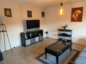 sala de estar con TV y mesa de centro en Ferienhaus-Naehe-Kochel-am-See en Großweil