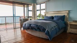 a bedroom with a bed with blue pillows and a balcony at Campismo Ninho Villa 26 - Ponta Malongane in Ponta Malongane