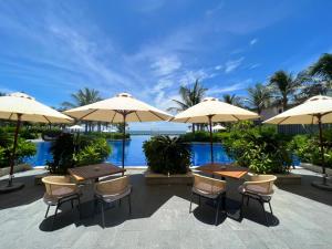 a patio with tables and chairs and umbrellas at Sea view villa in Wyndham Garden Cam Ranh in Nha Trang