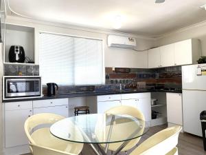 a kitchen with a glass table and chairs at Jedda on Jersey 6 in Perth