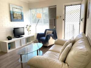 a living room with a white couch and a tv at Jedda on Jersey 6 in Perth