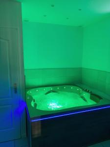 a large green bath tub in a room with blue lights at L’appart [é] spa in Beure