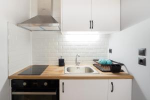 uma cozinha com um lavatório e armários brancos em Neoclassical Apartments with backyard acess em Atenas