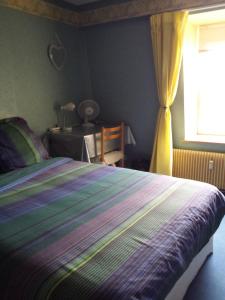 1 dormitorio con 1 cama con manta a rayas y ventana en Chambres d'hôtes Olry, en Nancy
