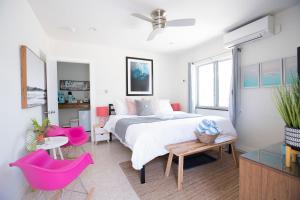 a bedroom with a large bed and pink chairs at Casa Limonada Boutique Motel in Sarasota