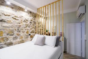 um quarto com uma cama branca e uma parede de pedra em Neoclassical Apartments with backyard acess em Atenas