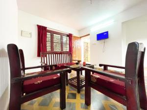 een woonkamer met een tafel en stoelen en een televisie bij Tranquiland in Kodaikānāl