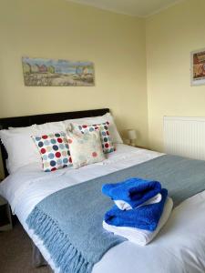 a white bed with blue towels on top of it at ORCHARD HILL HOUSE Apartment in Paignton