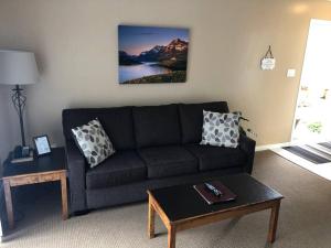 a living room with a black couch and a table at Paradise Canyon Golf Resort - Luxury Condo M403 in Lethbridge