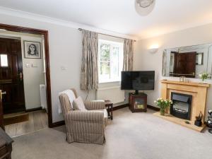 a living room with a television and a fireplace at Oakmead in Moreton in Marsh