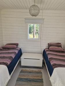 two beds in a room with a window at Liten stuga med fantastiskt läge in Tofta