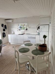 una cucina con tavolo e sedie e una cucina con armadietti bianchi di Liten stuga med fantastiskt läge a Tofta