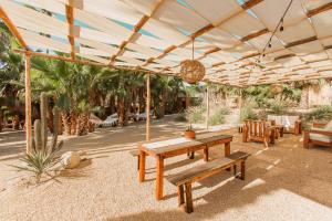 eine Terrasse mit einem Holztisch und Bänken unter einem Zelt in der Unterkunft Cien Palmas- Authentic Mexican Casita 1 -Downtown in Todos Santos